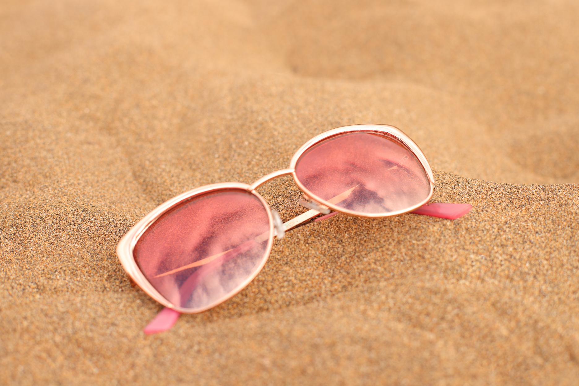 Sunglasses gold on beach sand, summer vacation accessory